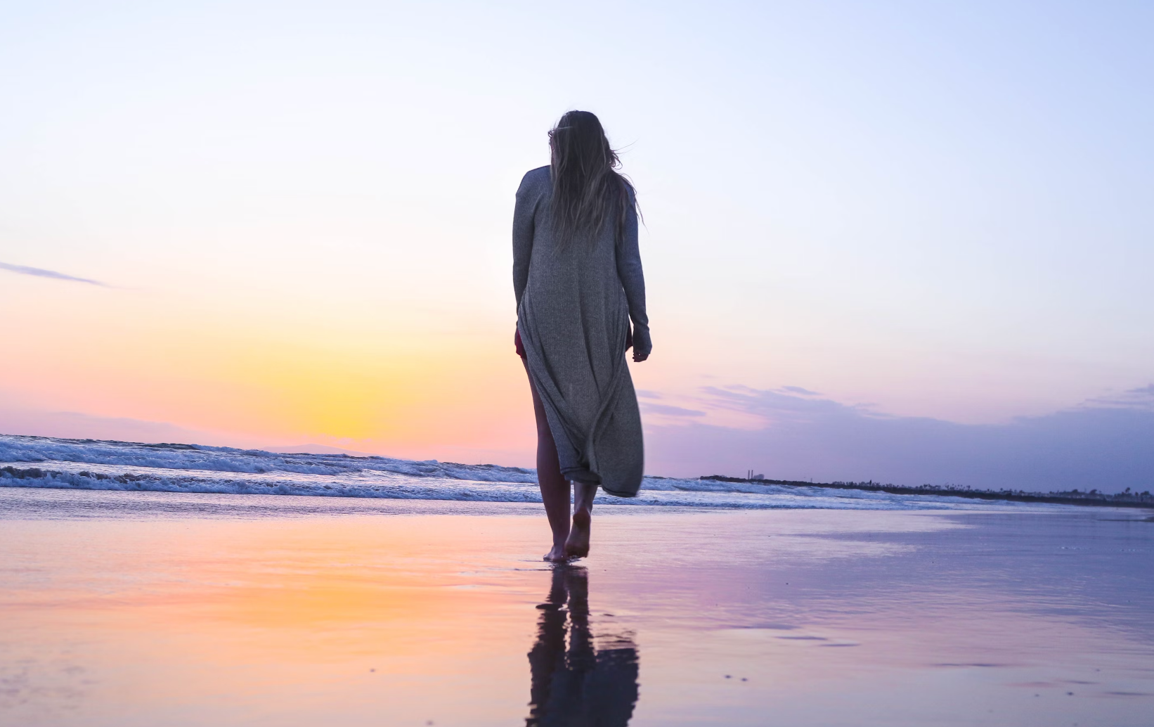 A woman walking along the beach at sunset, symbolizing calm and reflection during perimenopause.